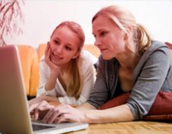 Imagem de mãe e filha a usarem o computador juntas. A imagem ilustra a importância da comunicação e de ajudar a sua filha a encontrar a informação certa.
