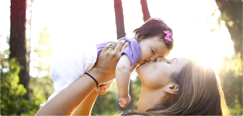 Imagem de uma mulher a pegar num bebé e a beijá-lo.